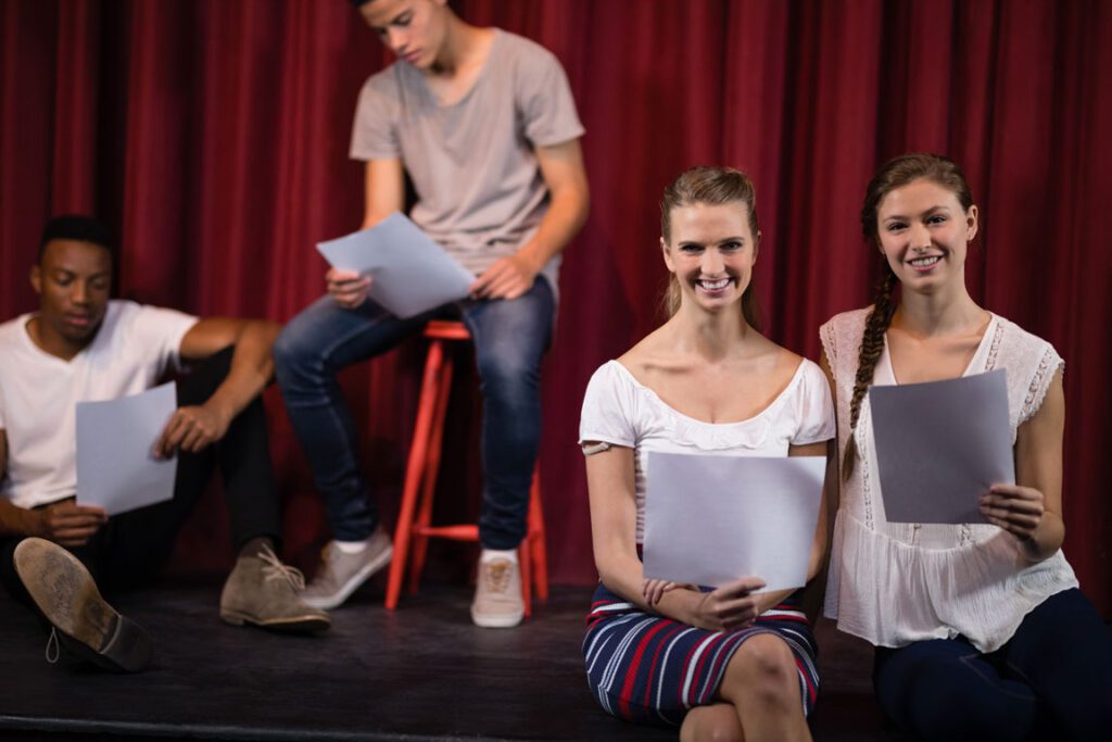 high school students sitting on stage rehearsing for a school play